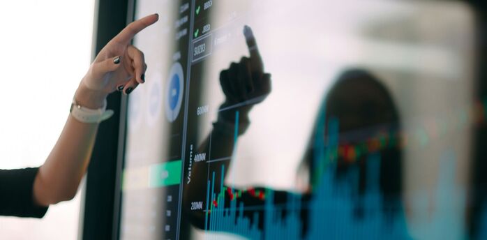 Person pointing at a digital screen displaying charts and data visualizations