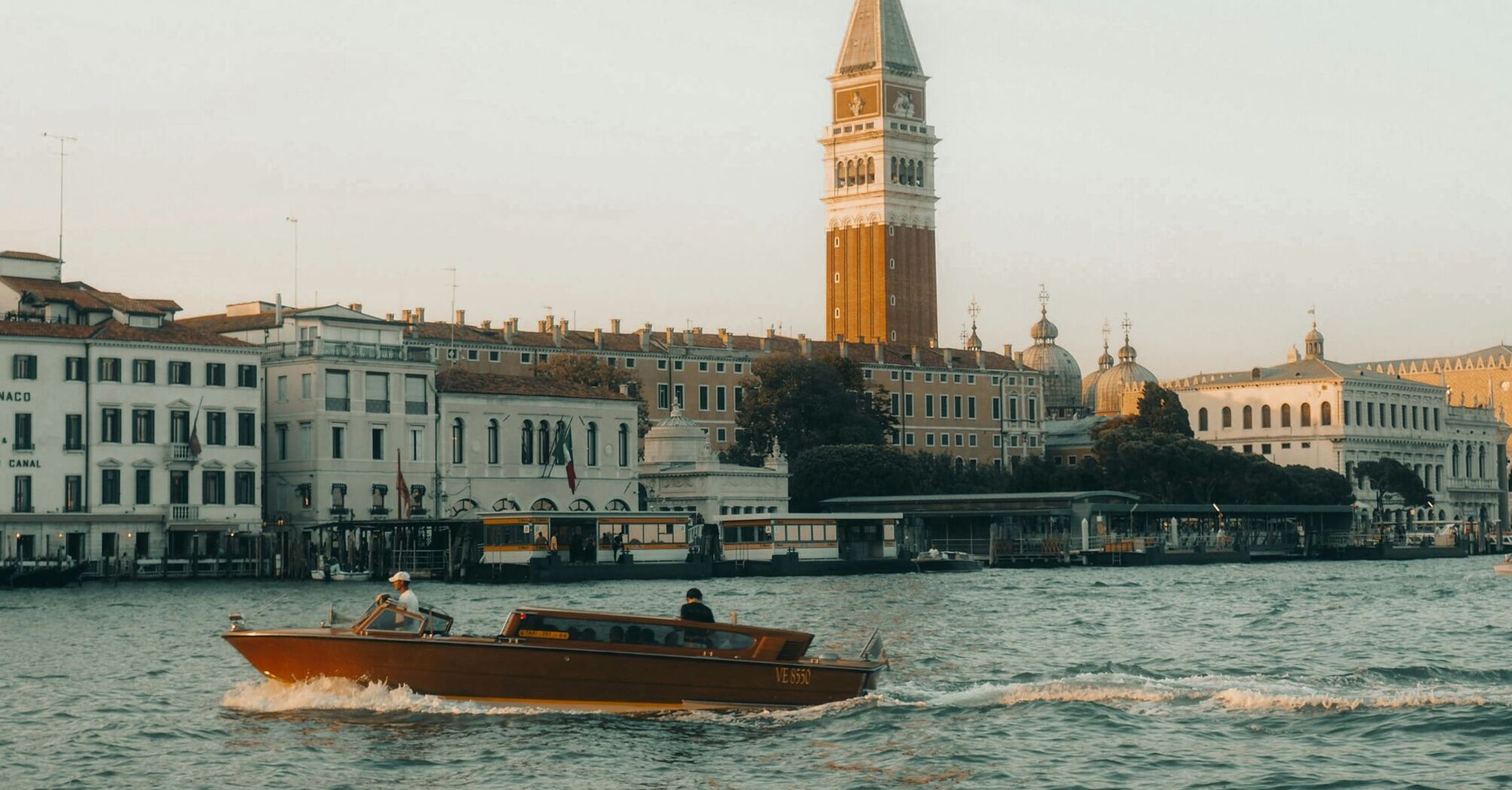 Water taxi passing St. Mark’s Campanile along the waterfront in Venice, Italy