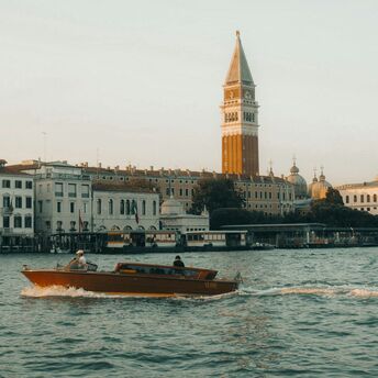 Water taxi passing St. Mark’s Campanile along the waterfront in Venice, Italy