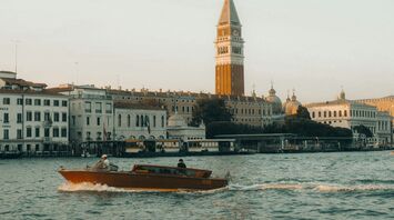 Water taxi passing St. Mark’s Campanile along the waterfront in Venice, Italy