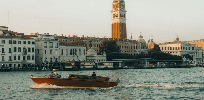 Water taxi passing St. Mark’s Campanile along the waterfront in Venice, Italy