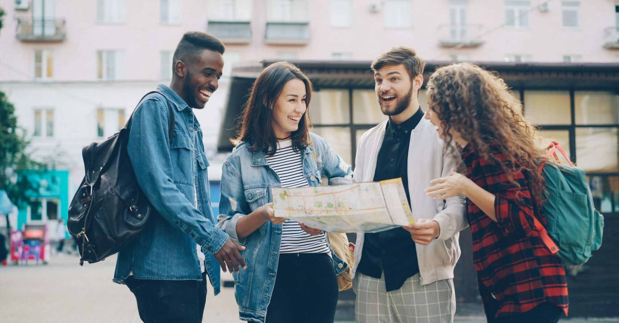 Four friends with backpacks looking at a city map together