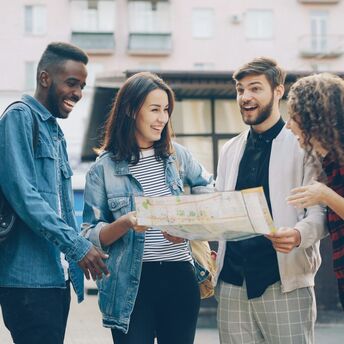 Four friends with backpacks looking at a city map together