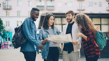 Four friends with backpacks looking at a city map together