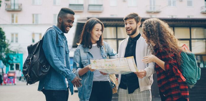 Four friends with backpacks looking at a city map together