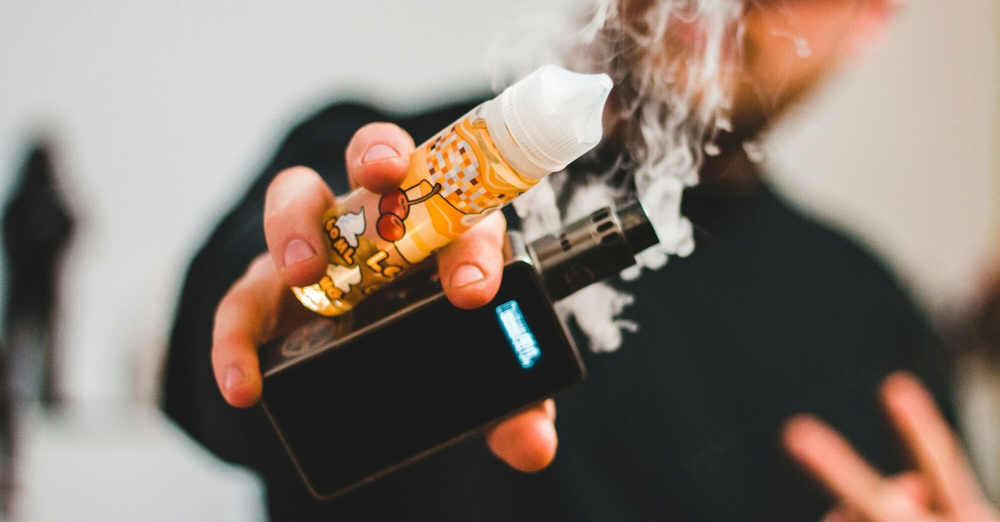 Person holding a vape and e-liquid bottle