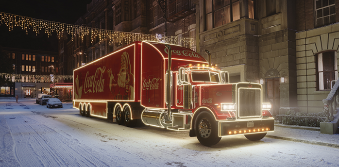 Illuminated Coca-Cola Christmas truck on a snowy street