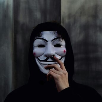 Person wearing a Guy Fawkes mask and black hood