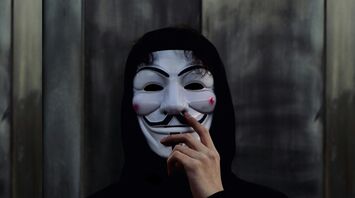 Person wearing a Guy Fawkes mask and black hood