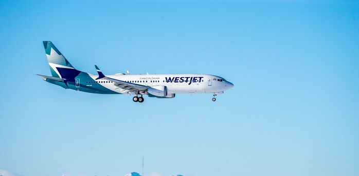 WestJet aircraft flying above snow-covered mountains