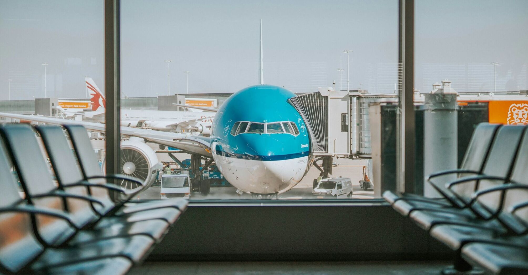 KLM aircraft parked at an airport gate, viewed through terminal windows