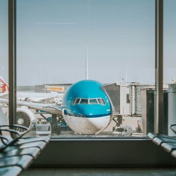 KLM aircraft parked at an airport gate, viewed through terminal windows