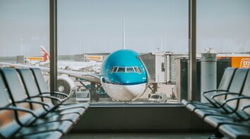 KLM aircraft parked at an airport gate, viewed through terminal windows