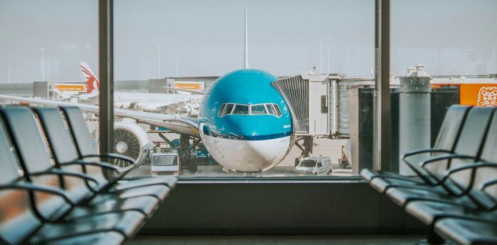 KLM aircraft parked at an airport gate, viewed through terminal windows