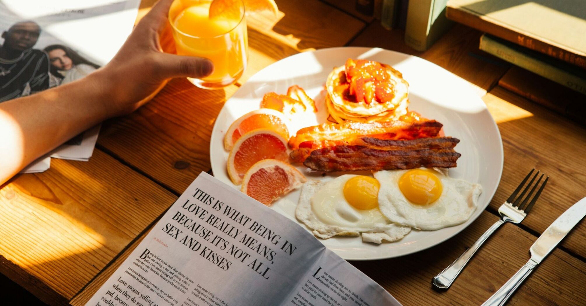 Plate of eggs, bacon and pancakes with orange juice on a breakfast table