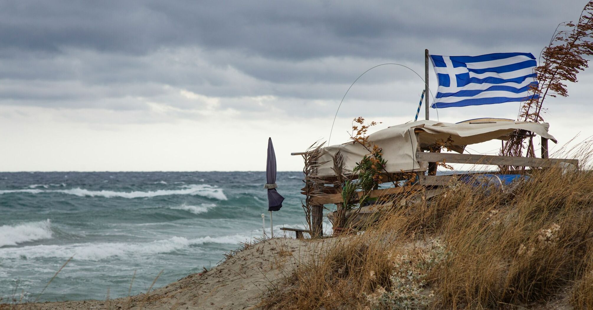 Greek flag beside rough sea in Crete