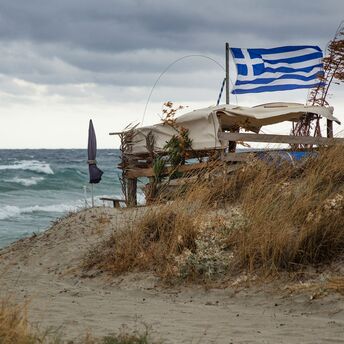 Greek flag beside rough sea in Crete