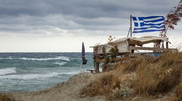 Greek flag beside rough sea in Crete