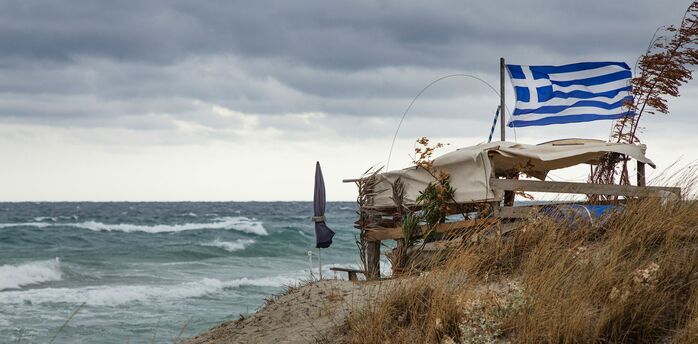 Greek flag beside rough sea in Crete