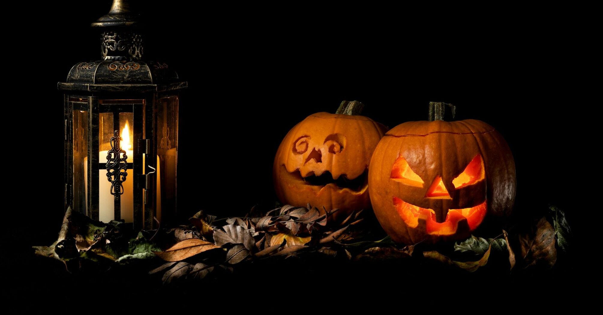 Glowing Halloween pumpkins beside lantern