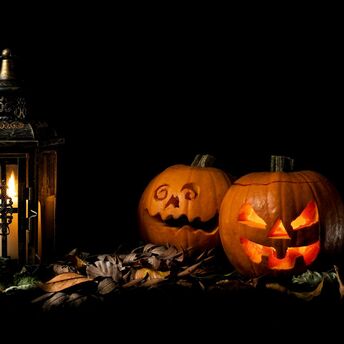 Glowing Halloween pumpkins beside lantern