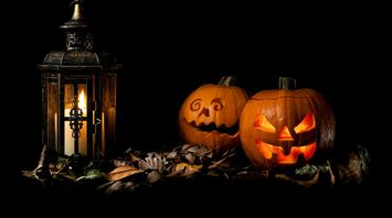 Glowing Halloween pumpkins beside lantern