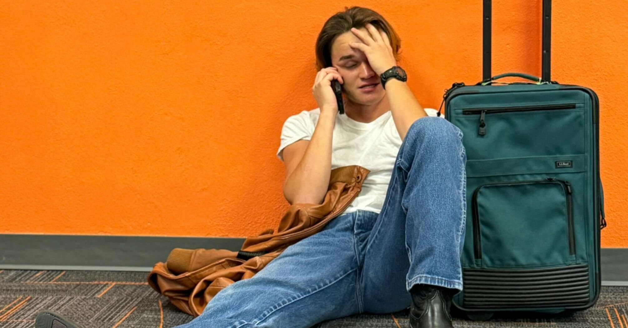 Stranded traveller sitting at airport with suitcase after flight cancellation
