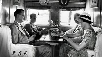Passengers socialising inside a vintage railway carriage in the 1930s