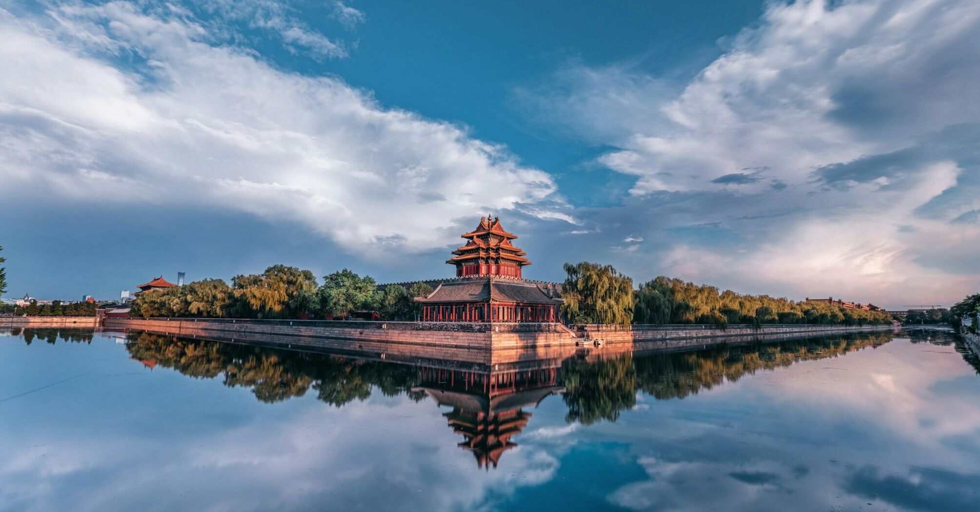 Corner tower of the Forbidden City reflected in water at sunset