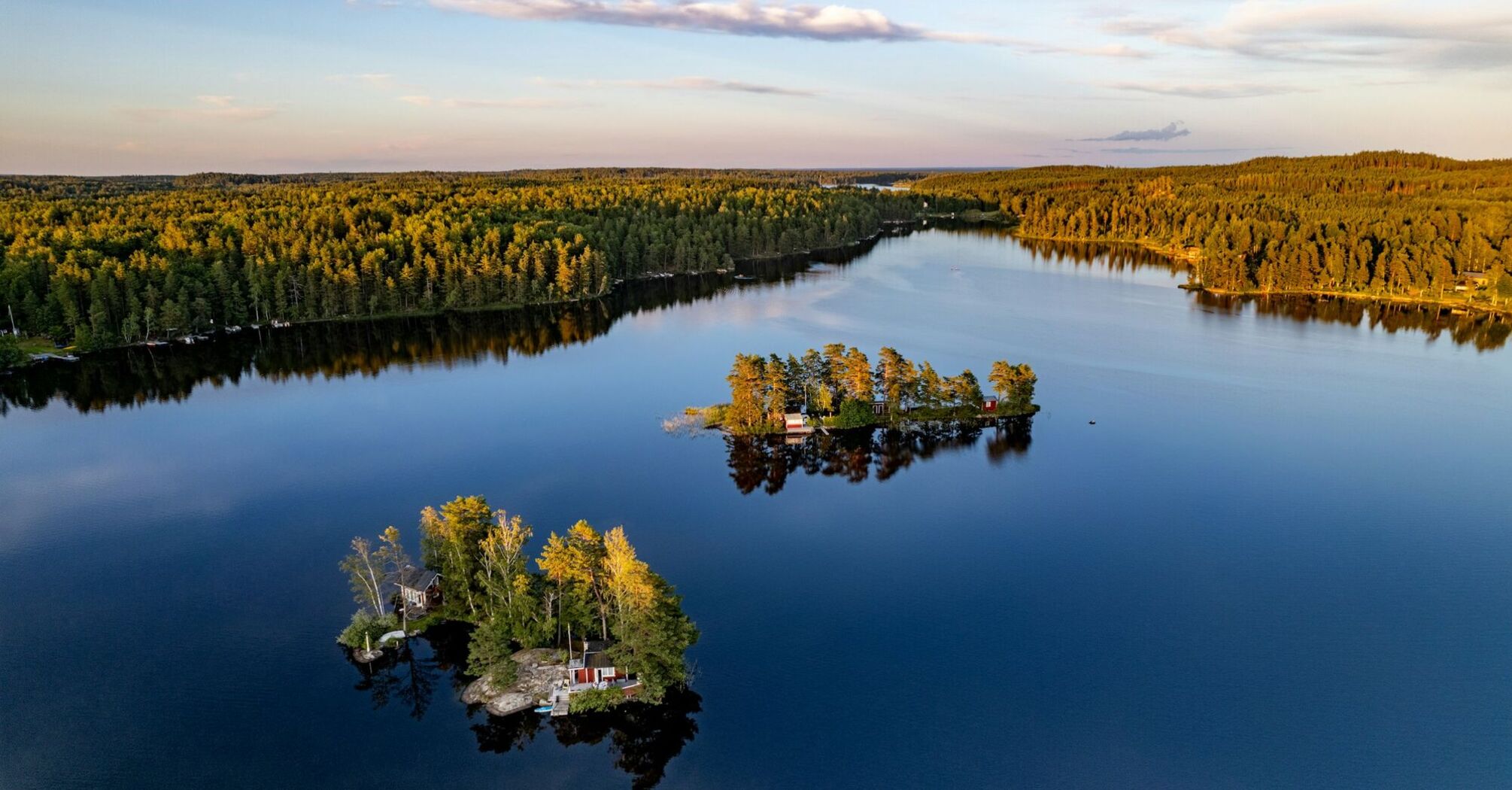 Aerial view of small forested islands on a calm Swedish lake at sunset