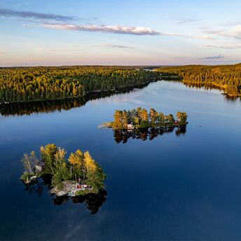 Aerial view of small forested islands on a calm Swedish lake at sunset