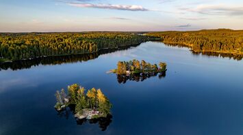 Aerial view of small forested islands on a calm Swedish lake at sunset