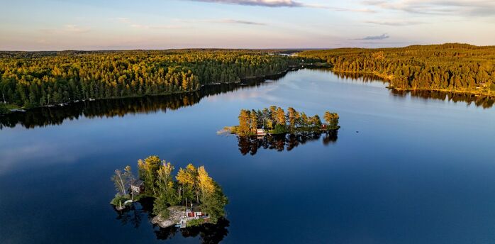 Aerial view of small forested islands on a calm Swedish lake at sunset