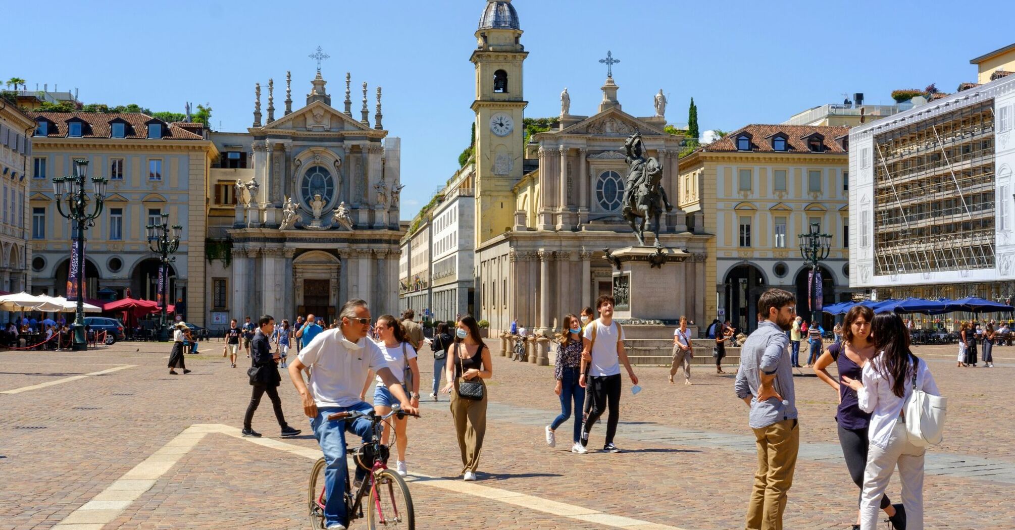 Historic square in Turin with baroque churches and people walking in sunlight