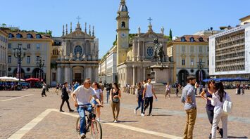 Historic square in Turin with baroque churches and people walking in sunlight