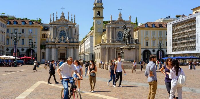 Historic square in Turin with baroque churches and people walking in sunlight