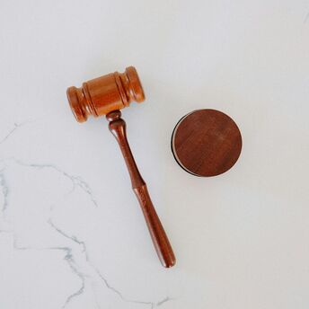 Wooden judge gavel and sound block on white surface