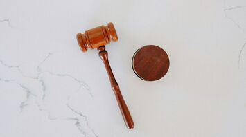 Wooden judge gavel and sound block on white surface