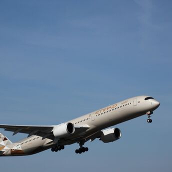Etihad Airways aircraft in flight against clear blue sky