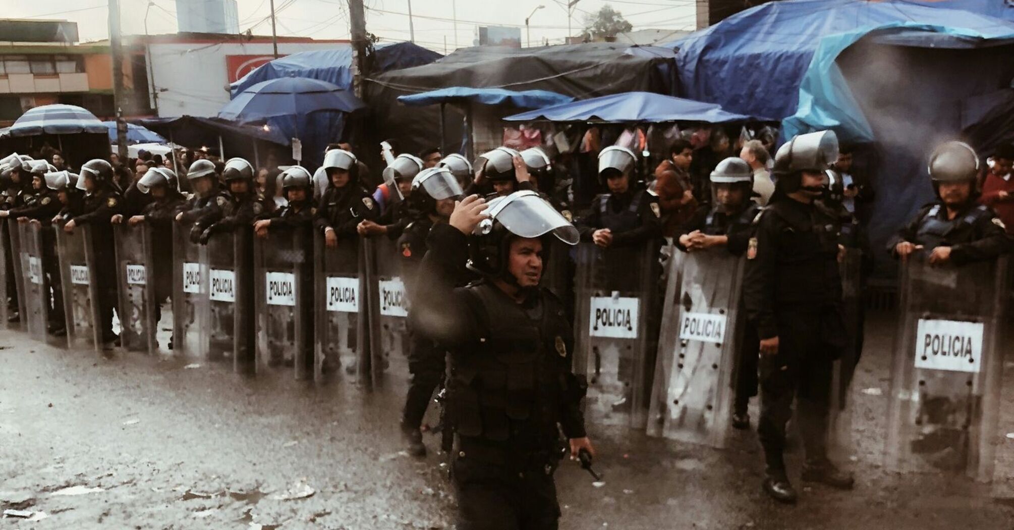 Riot police standing behind shields during street unrest in Mexico