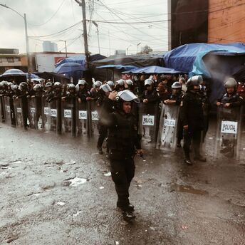 Riot police standing behind shields during street unrest in Mexico