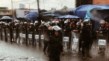 Riot police standing behind shields during street unrest in Mexico