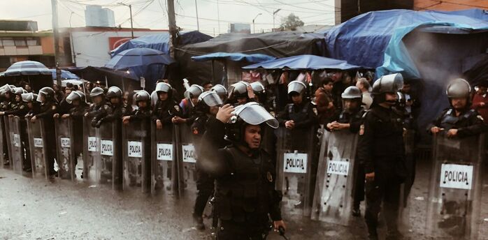 Riot police standing behind shields during street unrest in Mexico