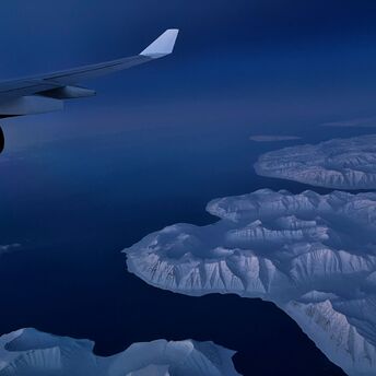 Aerial view of snow-covered Greenland coastline seen from aircraft window