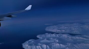 Aerial view of snow-covered Greenland coastline seen from aircraft window