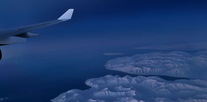 Aerial view of snow-covered Greenland coastline seen from aircraft window