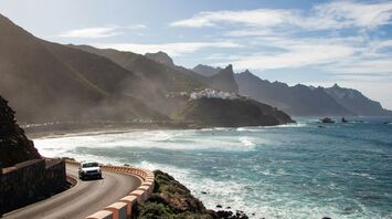 Coastal road and beach in Tenerife with mountains in background