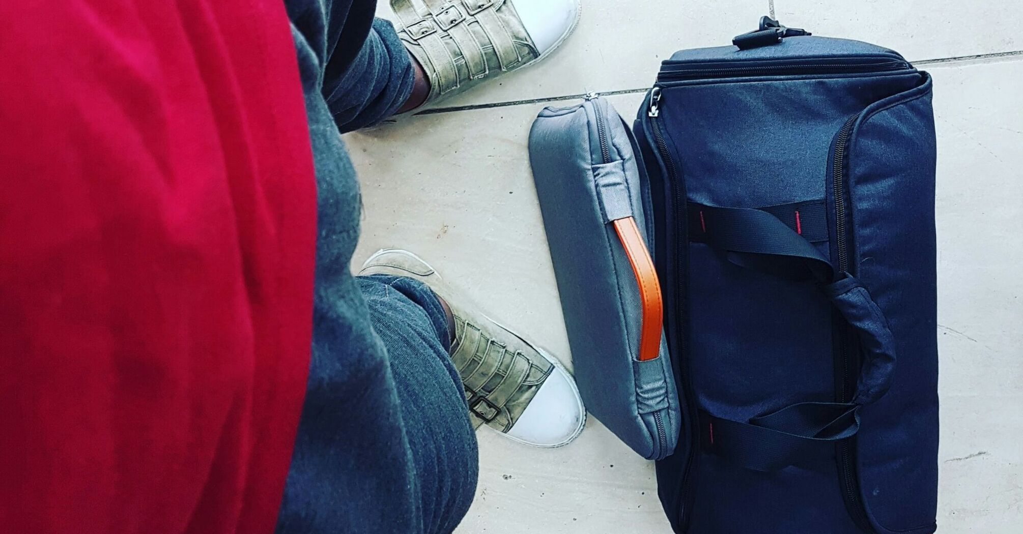 Traveller standing beside cabin suitcase and personal bag