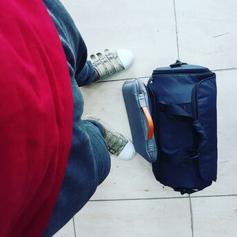 Traveller standing beside cabin suitcase and personal bag