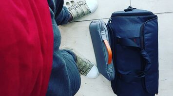 Traveller standing beside cabin suitcase and personal bag